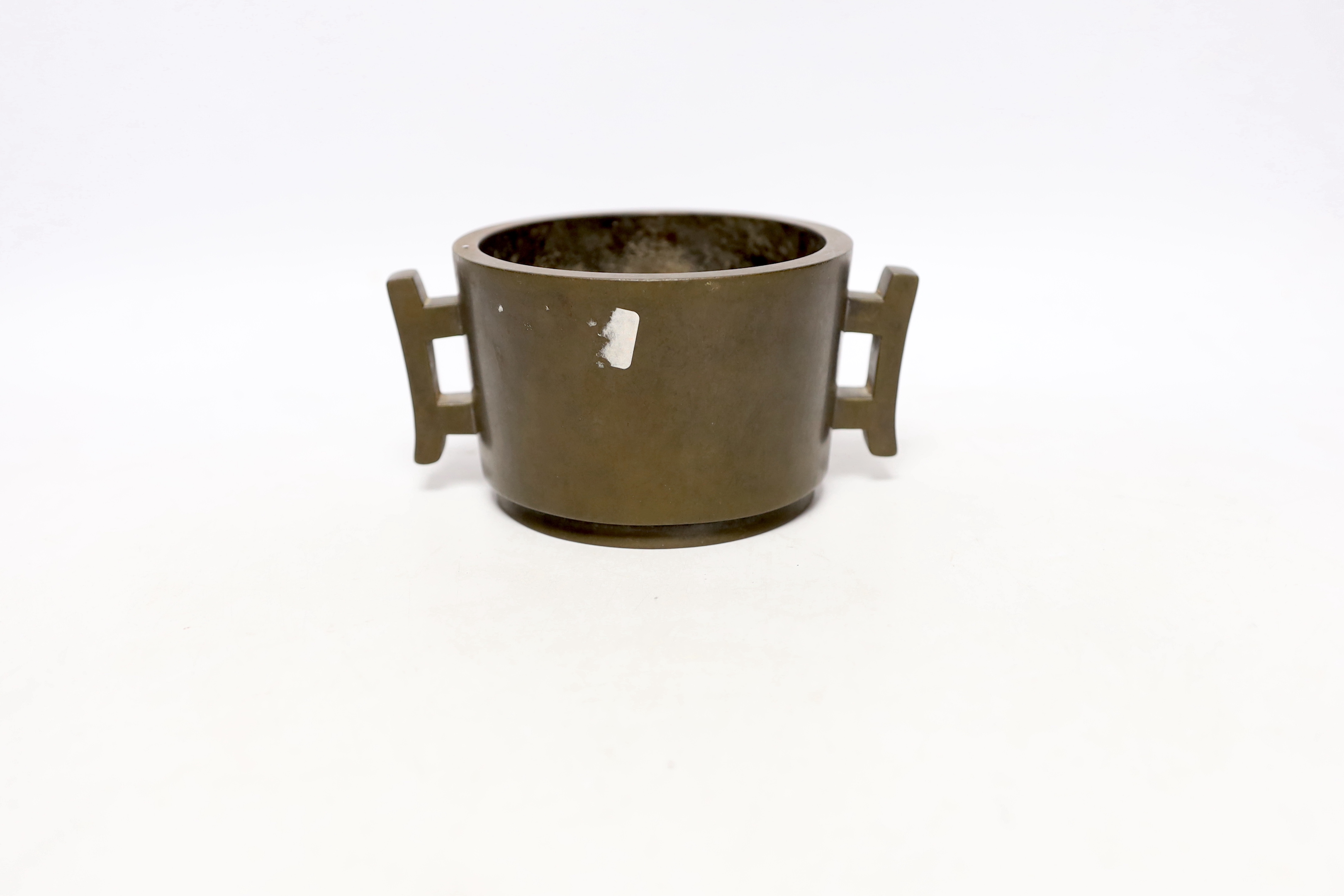 A Chinese bronze censer, of tapering cylindrical form, applied with a pair of trellis shaped handles, cast four character mark, 16cm wide